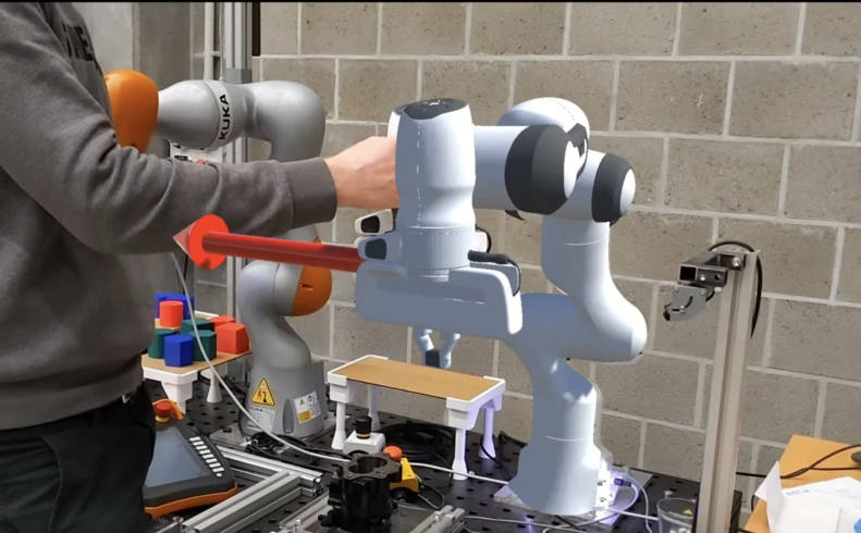 Augmented reality overlay on a robotic arm in an industrial setting, showing real-time digital twin visualization